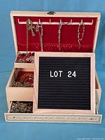 Full view of open white vintage jewelry case showing hanging necklaces and multiple shelf compartments with assorted costume jewelry.