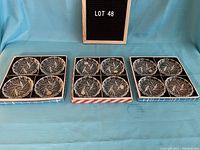 Three boxed sets of four crystal coasters arranged on a blue cloth, visible intricate cut designs.