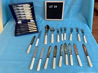 Flatware set and extra pieces arranged on blue cloth with a letter board showing lot number.