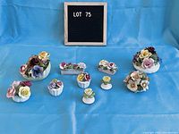View of eight different small decorative floral bouquets arranged on blue cloth with black felt letter board showing "LOT 75"