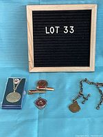Photo showing all small items: King George V coronation medal on chain, two Masonic temple tie clips (one round ER medallion and one red enamel rectangular tie clip), and bronze lodge medallion on chain.