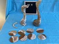 Photo showing two onyx marble sculptures—a swan and a dog figure—and six hexagonal onyx coasters, with the dog's tail separate.