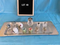 Entire salt and pepper shaker assortment on rectangular metal tray, displaying variety of materials and shapes.