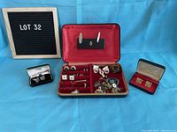 Wide shot showing all boxes and organizer containing assorted tie clips and cufflinks.