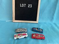 Photo of four vintage diecast cars arranged on blue background next to Lot 23 sign
