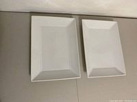 Two white rectangular porcelain serving platters placed side by side for size and shape comparison.