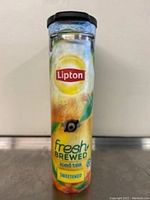 Front view of tall narrow iced tea dispenser with Lipton branding and dispensing valve near bottom