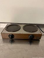 Front view of Bunn O Matic 2 burner electric hot plate showing both burners and control knobs on wood grain finish panel.