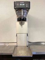 Front view of tall stainless steel Bunn coffee brewer on countertop showing base and drip tray