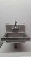 Front view of stainless steel wall mount hand sink showing basin and faucet with hot and cold water controls.