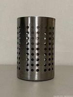Front view of cylindrical stainless steel utensil holder showing uniform round perforations.