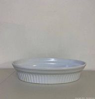 Side view of the white porcelain oval baking dish showing ribbed texture on outer sides.