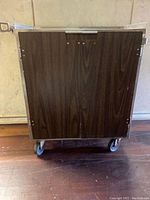 Front view of the cart showing wood finish double doors on caster wheels.