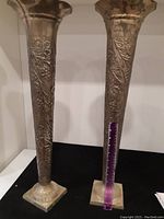 Two trumpet vases standing upright next to a ruler showing approximately 24 inches tall.