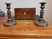 Photo of vintage wooden box and pair of expandable metal candle holders on wooden surface