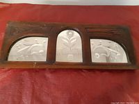 Full view of rectangular wooden frame with three arched mirror sections etched with floral designs.