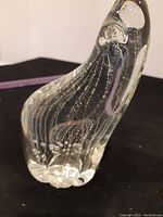 Close-up of the base and lower body of the blown glass polar bear showing bubbles inside the clear glass and the smooth rounded feet.