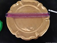 Top view showing the gold-toned round trophy plate with scalloped edges and a purple ruler measuring approximately 12 inches across.