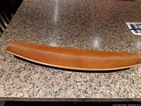 Full view of the teak canoe-shaped bowl on granite surface showing its curved elongated form and condition.