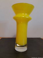 Front view of bright yellow vase on flat surface, showing shape details and color.