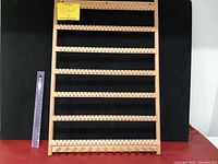 Full front view of wooden earring display rack with black background and ruler for scale