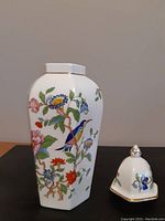 Front view of hexagonal urn showing colorful floral and bird design on white fine bone china.