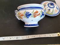Side view of the Quimper ceramic lidded bowl with handles and floral hand-painted decoration, bowl shown with lid off.