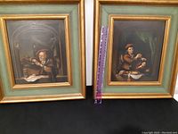 Two framed antique paintings together showing a man writing and another man gesturing indoors, both set in gold-tone frames with green mats.