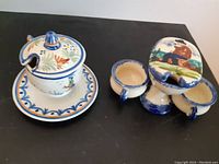 Photo of two Quimper condiment holders showing lidded pot with plate and double cup holder with lid