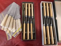 Overview of all knives with two boxed sets and one set in plastic bags on red surface.