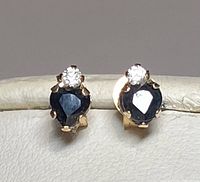 Pair of stud earrings with heart-shaped blue sapphires and small white diamonds set in 10K gold.