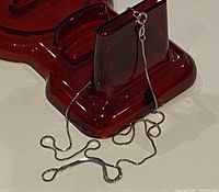 10K white gold fine chain loosely arranged on a dark red object.