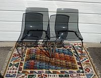 Front view of both chairs showing smoked grey Lexan seats and chrome cantilever bases on patterned rug
