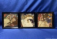 Photo showing all three framed abstract prints arranged side by side against a blue fabric backdrop.