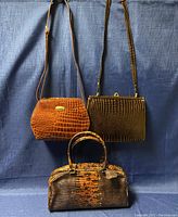 Three vintage ladies purses displayed together hanging and resting on fabric background