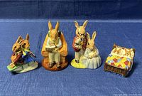 All four Royal Doulton Bunnykin porcelain figurines arranged on blue fabric background showing full set