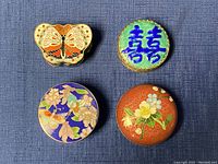 Top view of all four cloisonné trinket boxes showing colorful enamel butterfly, floral, and symbol designs.