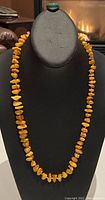 Full view of amber nugget necklace displayed on a black bust form.