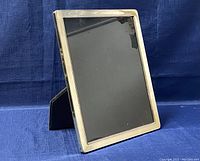 Front view showing large rectangular silver photo frame with reflective silver border and black display stand.