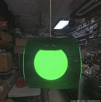 Pendant light hanging in workshop, showing green acrylic shade and white globe