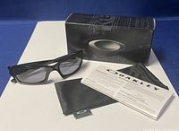 Overall lot showing sunglasses, original box, pouch, and information booklet on white background.