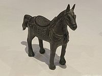 Front angled view of vintage cast bronze horse sculpture showing detailed saddle and harness