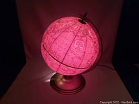 Globe lit up showing constant red illumination inside the globe, metal base visible.