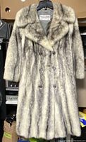 Front view of the vintage wolf fur coat hanging on a hanger. Shows full length and button details.