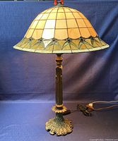 Full view of the lamp with stained glass shade, showing the detailed color and design of the glass panels and the ornate metal base.
