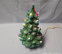 Front view of the ceramic Christmas tree showing green textured branches with embedded colored bulbs lit.