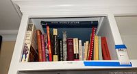 Books on a high shelf, wide view showing multiple theater books and an atlas on top.