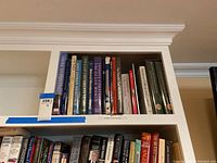 Shelf of assorted coffee table books including titles related to American painting, Indian heritage, ocean exploration, historical mysteries, and more.