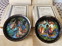 Two collectible plates displayed with Certificates of Authenticity. Painted scenes show Russian folklore characters and settings. Plates are inside original boxes.