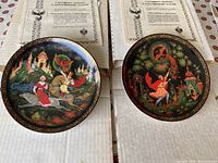 Two collectible plates from The Legend of the Firebird collection shown with original boxes and certificates of authenticity in Russian.